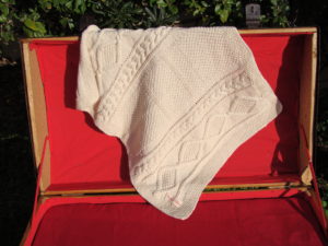 Couverture bébé en coton bio présenté sur une malle ancienne. Création originale : La malle au Coton