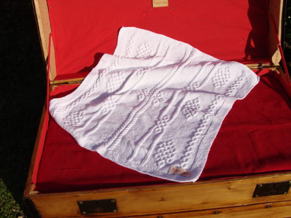 Couverture bébé 100% coton présentée sur une malle ancienne. Création originale : La malle au Coton -W1