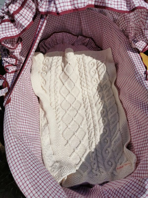 Plaid bébé en coton naturel présenté dans couffin
